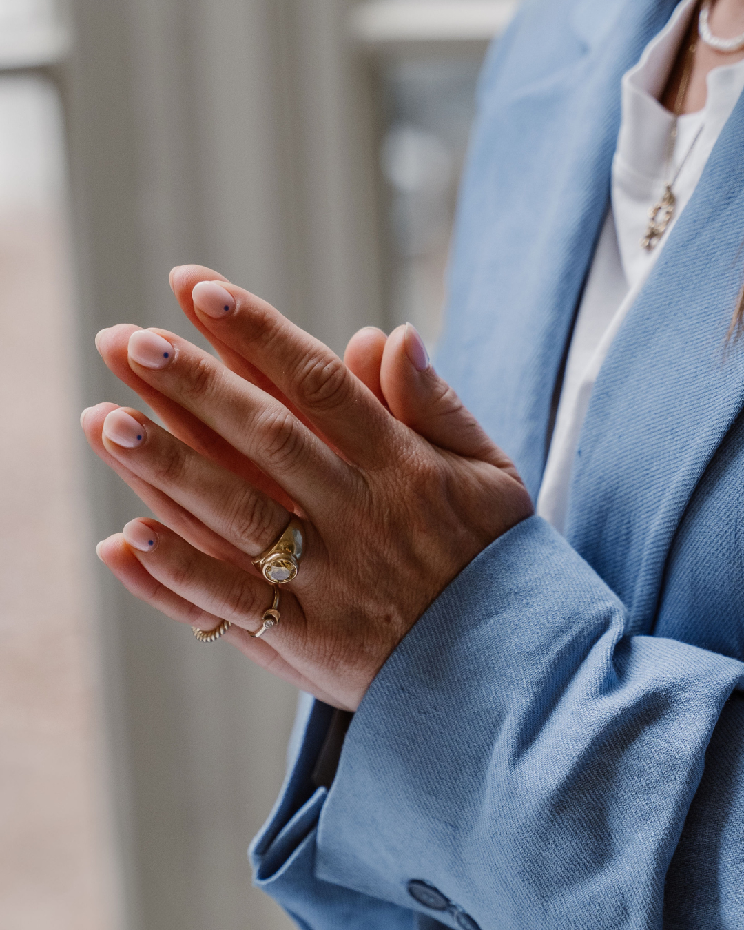 Detail van Hanneke Peeters' handen met ringen bij een blauw colbert